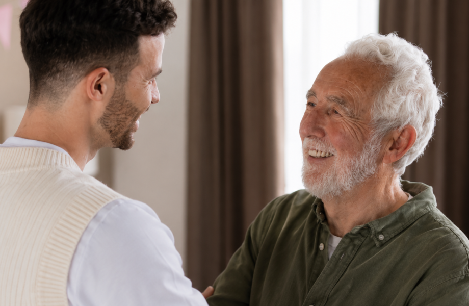 A caregiver sharing a warm conversation with an older man at home